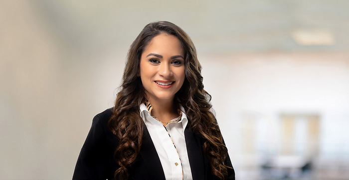 Professional photo of woman smiling with curly brown hair wearing a black blazer jacket
